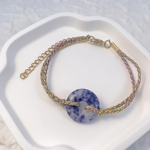 Detail of hand-woven bracelet with blue natural stone ring and golden extension chain