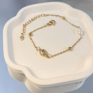 Detailaufnahme der vergoldeten Edelstahlarmband mit Perle und tropfenförmigem Zirkon