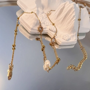 Dettaglio della collana dorata con cristallo a goccia e perle su base di pietra bianca