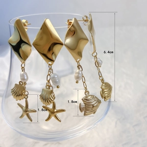 Golden ocean theme earrings with starfish shell charms and pearls on a glass rim