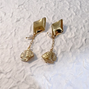 Detail of gold tropical fish drop earrings featuring white pearls and geometric studs
