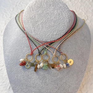 Detail of bohemian necklaces with woven ropes, natural stones, pearls and sun pendants