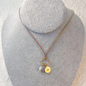 Detail of colorful braided rope necklace with pearl, stone and golden sun eye charm