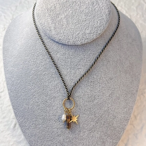 Detail of woven rope necklace featuring pearl, tiger eye stone and gold star charms
