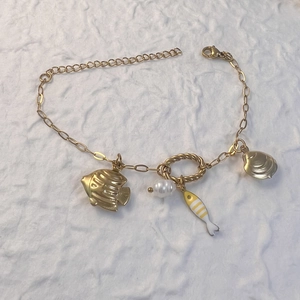 Details des goldenen Ozean-Armbands mit Seestern-, Muschel-, Perlen- und Fisch-Anhängern
