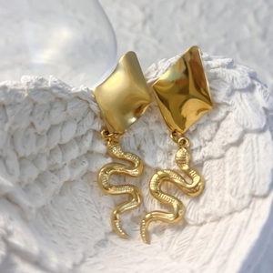 Detailed close-up of golden snake earrings with intricate scale texture and polished finish