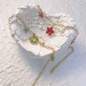 Bracelet chaîne trombone doré avec breloques étoiles colorées et perles sur plateau