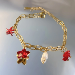 Détail du bracelet chaîne dorée avec pendentif étoile de mer rouge et perles d'eau douce