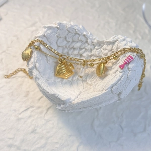 Détail du bracelet doré multicouches étoile de mer et perle dans un bol en forme de cœur