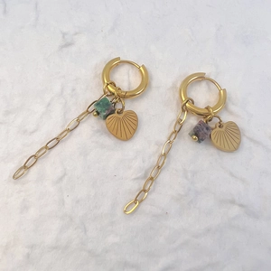 Detail of gold dangle earrings featuring heart charms, green beads, and link chains