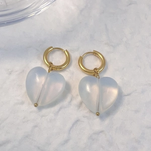 Eleganti orecchini a cuore in quarzo con cerchi dorati su sfondo materico raffinato