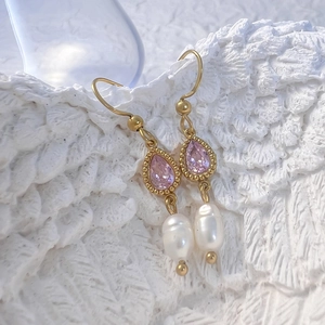 Détail de boucles d'oreilles dorées avec pierre rose poire et perles baroques