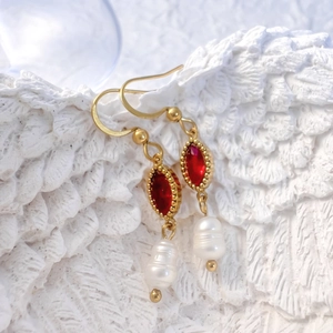 Détail des boucles d'oreilles perles en forme de goutte avec zircon rouge et or