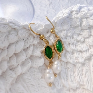 Détail de boucles d'oreilles dorées avec pierres marquise vertes et perles d'eau douce