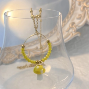 Detail der Pilzhalskette mit goldenem Ring und gelben Perlen am Glaskelch