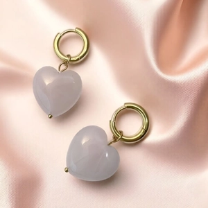 Detail of heart-shaped rose quartz pendant on a gold stainless steel hoop earring