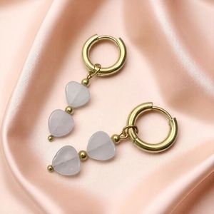 Detail of gold geometric earrings featuring two translucent heart-shaped natural stones