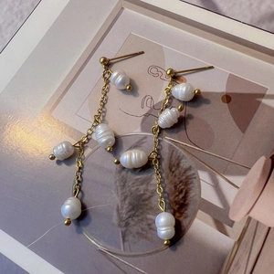 Detail von Süßwasserperlen-Quastenohrringen mit Goldkette in einem künstlerischen Stillleben