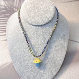Close-up of colorful mushroom pendant with vibrant three-color braided rope necklace