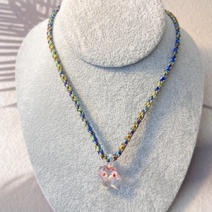 Close-up of colorful braided rope necklace with a cute pink resin mushroom pendant