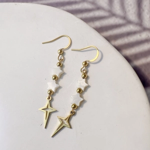 Detail of gold star earrings with white shell pentagrams and hollow star pendants