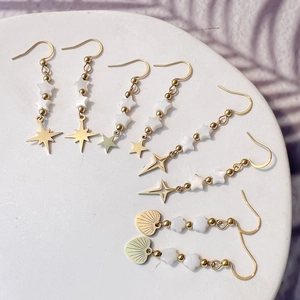 Elegant gold star and heart shell drop earrings set on white stone base display