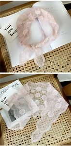Close-up of floral lace embroidery and scalloped edges on a light pink triangle scarf