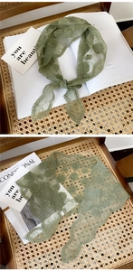Close-up of green lace triangle scarf with floral embroidery and wavy scalloped edges