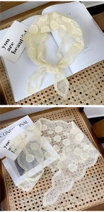 Close-up of beige floral lace scarf with delicate embroidery and scalloped edges