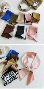 Macro shot of assorted colorful satin skinny scarves displayed on a woven summer bag