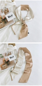 Detail of elegant two-tone silk scarf in beige and champagne gold tied in a chic knot