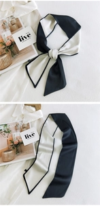 Close-up of double-sided black and white silk ribbon scarf tied in a bow with magazine