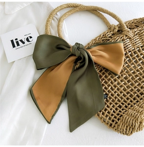 Detail of a silk satin bow ribbon scarf in dark green and mustard yellow color contrast
