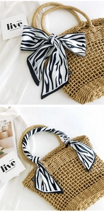 Detail of zebra pattern silk ribbon bow tied on a straw mesh tote bag handle