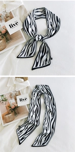 Detail of double-sided zebra pattern skinny silk scarf tied on white fabric