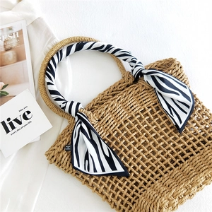 Woven straw handbag with zebra print silk scarf tied on handle for summer vacation style