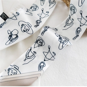 Close-up of a white polyester scarf featuring abstract navy blue line art facial patterns