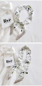 Close-up of white narrow silk scarf with winter cartoon prints tied on a white shirt