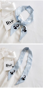 Detail of light blue silk scarf with floral patterns and illustrations on white shirt
