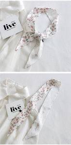 Close-up of narrow floral silk scarf tied elegantly on a white shirt collar