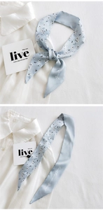 Detail of light blue floral skinny scarf with Green inspiration ground print text