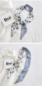 Detailed close-up of skinny silk scarf with rose floral patterns and elegant lettering