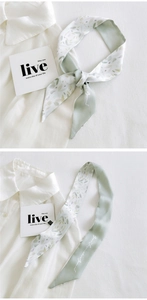 Detail of floral silk scarf ribbon with botanical patterns and script print on white shirt