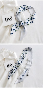Detail of white narrow silk scarf with blueberry print tied on a classic white shirt