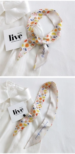 Detail of slim satin scarf with colorful fruit print tied on a crisp white shirt