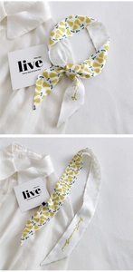 Detail of a white narrow silk scarf with yellow pear print on a white shirt collar