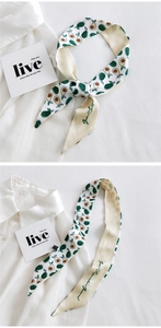 Detail of a white silk twilly scarf with green avocado prints on a white shirt
