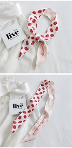 Detail of a slim silk scarf with grapefruit print tied on a white linen shirt