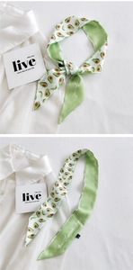 Detailed view of long silk scarf with avocado print on textured white fabric