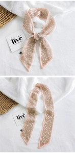 Detail of pink floral silk scarf tied as a bow on minimalist natural fabric background